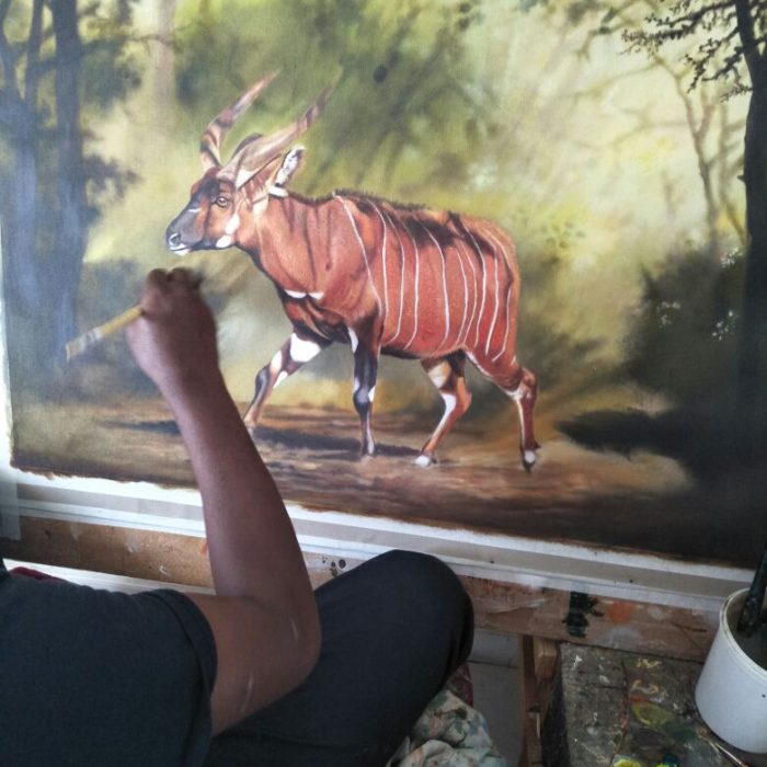 Artist Daniel Njoroge hand-painting a mountain bongo in the forest